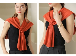 Detail of orange knitted shawl with a stylish cross-knot design on casual attire