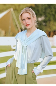 Detail of mint green knit shawl draped over a matching satin shirt and olive trousers