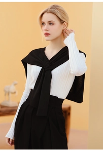Detail of elegant white ribbed knit top paired with a chic black knit shawl