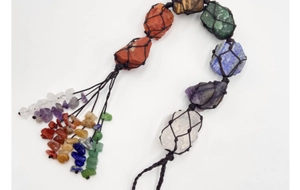 Dettaglio dell'ornamento appeso 7 chakra con pietre grezze rete intrecciata e nappe di pietra