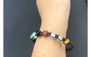 Close-up of handmade woven bracelet with seven colorful natural crystal beads on a wrist