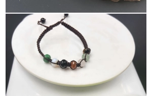 Macro detail of handmade braided chakra bracelet with seven colorful faceted crystal beads