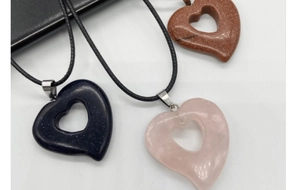 Detailed view of heart-shaped crystal stone pendants in blue, pink, and reddish brown