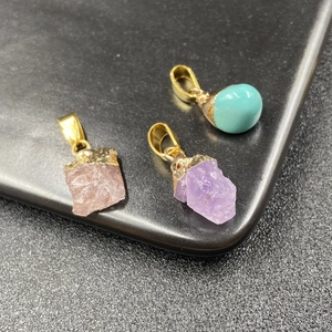 Natural amethyst and turquoise raw stone pendants with gold metal bail on black background