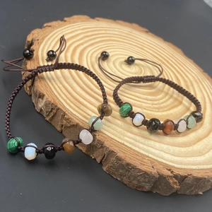Handmade woven rainbow crystal bracelet with natural healing stones on a wooden stand