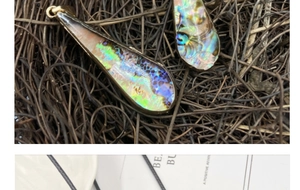 Macro view of teardrop abalone shell pendant with golden edges and colorful luster