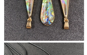 Close-up of teardrop abalone shell pendants with gold trim on black woven cords