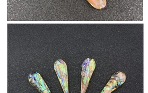 Close-up of teardrop abalone shell pendants with golden edges in multiple colors