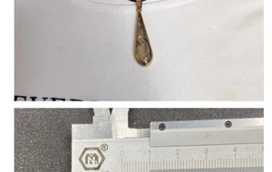 Detailed close-up showing shell pendant dimensions measured with a caliper tool