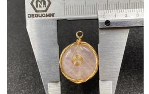 Detail of rose quartz pendant with gold wire wrapping measured by a caliper