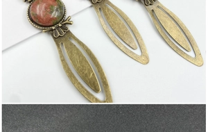 Close-up of vintage bronze owl bookmarks featuring natural gemstone cabochon inlays