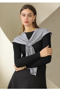 Detail of grey knitted shawl knotted over a slim black ribbed top for elegant styling