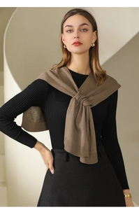 Detail of elegant khaki knitted shawl styled with a black sweater on minimalist stairs