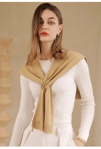 Detail shot of khaki knitted shawl over white cable knit sweater with refined texture