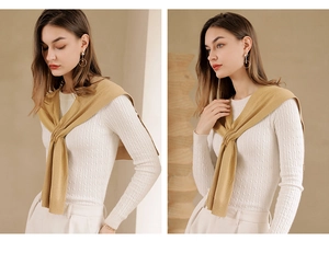 Detail showing elegant ginger yellow knitted shawl draped over white knitwear