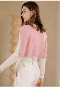 Detailed view of pink knitted shawl layered over white cable knit sweater for women