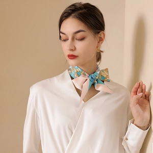 Elegant floral silk scarf in blue and pink tied around the neck on white satin shirt