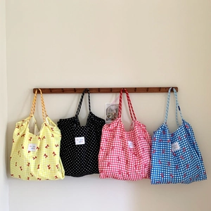 Detailed set of four fabric tote bags in plaid and polka dot patterns hanging on a rack