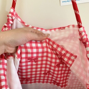 Detail view of red checkered tote bag with bow print and cotton rope handles