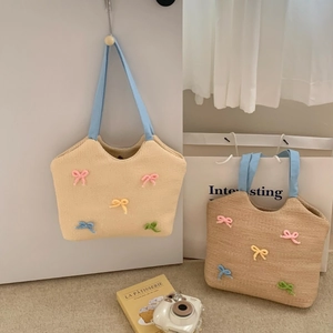Summer woven shoulder bag with colorful knitted bows and light blue fabric handles