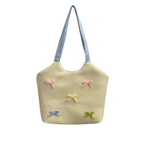 Summer straw woven shoulder bag with colorful 3D bows and blue straps on white background