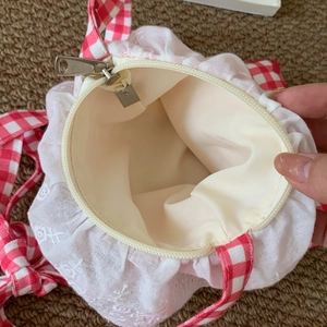 Close-up of internal storage with metal zipper and red gingham strap detailing