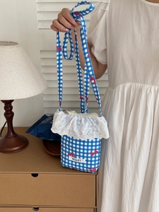 Detail of blue gingham phone bag with red bows, lace trim and Bisket brand label