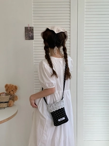 Close-up of the black polka dot lace bag styled with a white puff sleeve dress