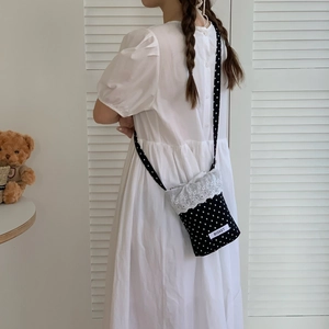 Polka dot mini crossbody bag with lace trim and drawstring closure on a model
