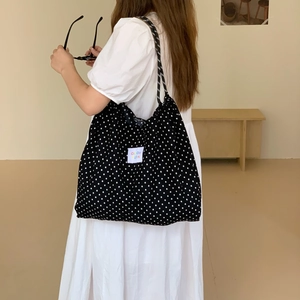Large black canvas tote bag with white polka dots and logo patch for daily commuting