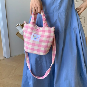 Detail of pink gingham canvas bag featuring an OiO-OiO PUFIN label and woven strap