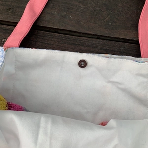 Detailansicht des Magnetverschlusses und der rosa Webgriffe an der gestreiften Stofftasche