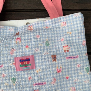 Nahaufnahme der blau karierten Tragetasche mit bunten Patches und rosa Herz-Detail