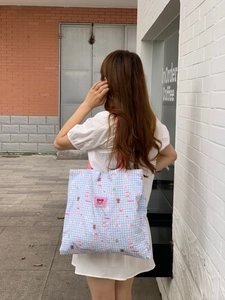 Detailansicht der blau gestreiften Tragetasche mit Cartoon-Prints und rosa Logo-Etikett