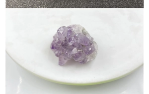 Vue macro d'un amas de cristaux d'améthyste naturelle sur un plateau blanc avec détails
