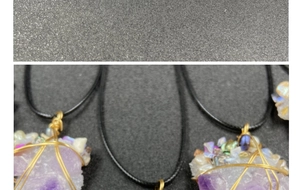 Macro shot of handmade amethyst crystal pendant with gold wire wrapping on a black cord