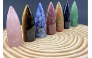 Set of seven bullet-shaped crystal energy stones arranged on a natural wood slice base