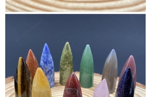 Polished crystal bullet-shaped stones and energy quartz displayed on a wood tray