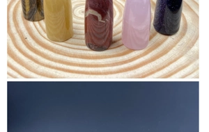 Macro detail of polished tiger eye and rose quartz cylinders on a rustic wooden tray