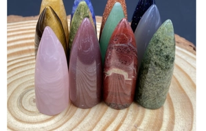Close-up of polished bullet-shaped crystal points made of quartz and agate on a wood base