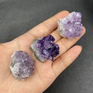 Grappes de cristaux d'améthyste naturelle tenues à la main montrant la texture minérale