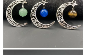Détail de pendentifs en croissant de lune avec pierres gemmes vertes, bleues et brunes