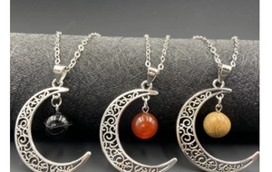 Trois colliers avec pendentif lune et perles en pierre naturelle sur support noir