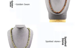 Detail view of Golden Swan and Spotted stone beaded necklaces on dark neck busts