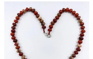Close-up of red and brown natural stone beads with lobster clasp and woven cord detail