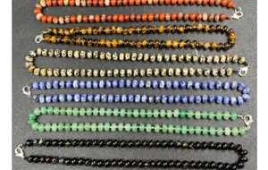 Detail view of colorful natural stone bead necklaces with silver lobster clasps on grey background