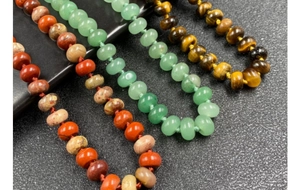 Macro shot of natural stone wheel beads with manual knotting on a textured background