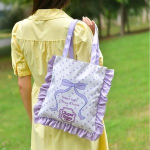 Close-up of cute purple ruffle trim and bow pattern on a white canvas tote bag