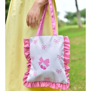 Detailed view of pink striped canvas tote bag with ruffles and cherry bow print
