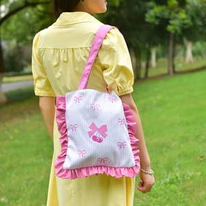Close-up of pink striped canvas tote bag with ruffle trim and bow cherry print
